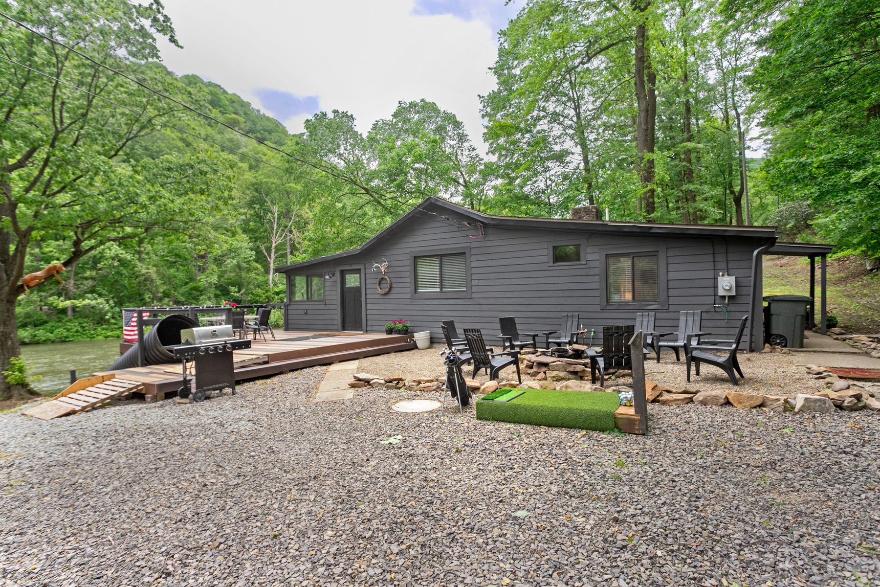 Cabin exterior with deck, firepit, and golf area along the creek
