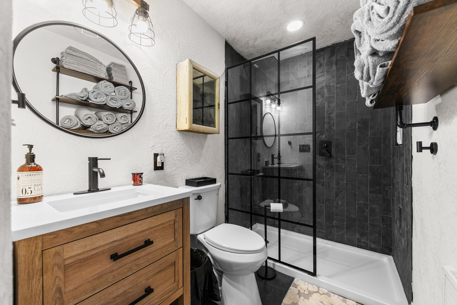 Renovated bathroom with black tile shower and wood vanity