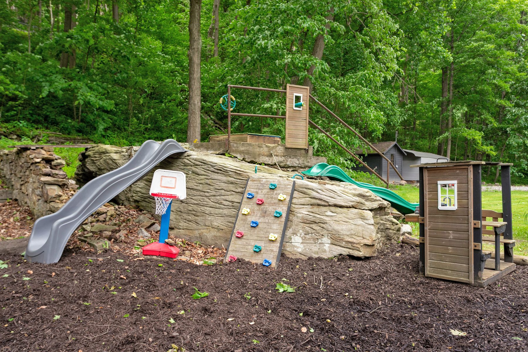 Kids' play area with slides, rock wall, basketball hoop, and playhouse